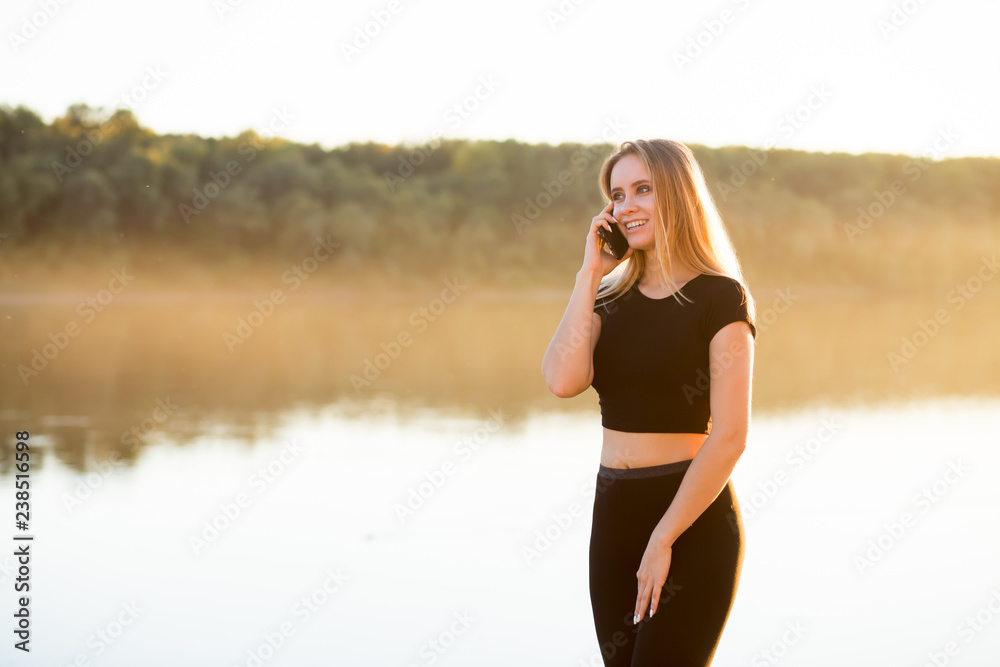 Beautiful fitness woman talking on a smartphone while Jogging in nature Beautiful fitness woman talking on a smartphone while Jogging in nature