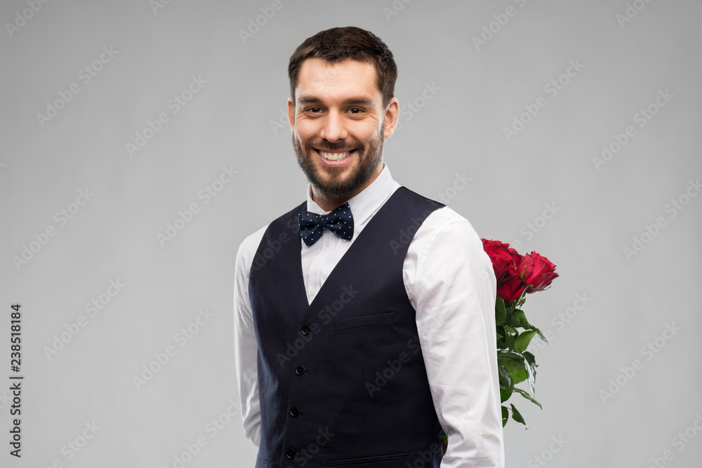 valentines day, greeting people concept - happy man in party clothes with red roses behind his back over grey background valentines day, greeting people concept - happy man in party clothes with red roses behind his back over grey background