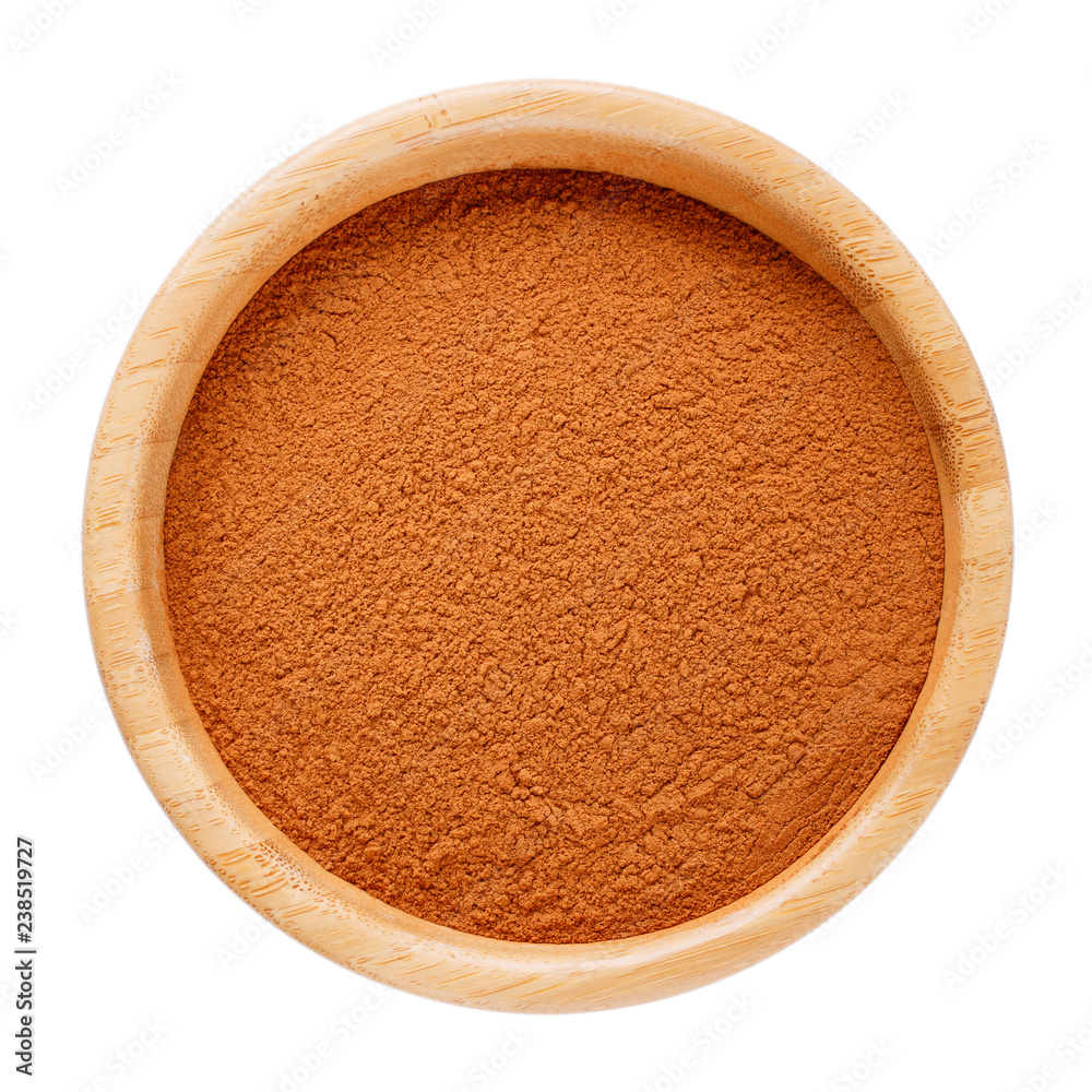 Ground cinnamon in wooden bowl isolated on white. Top view.
