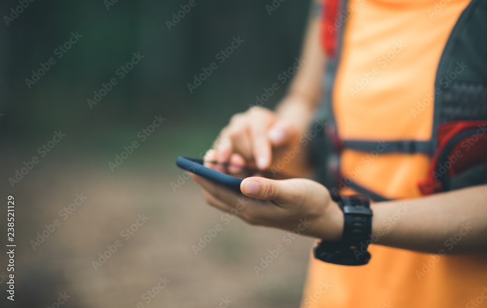 Sportswoman trail runner using smartphone for navigation in forest