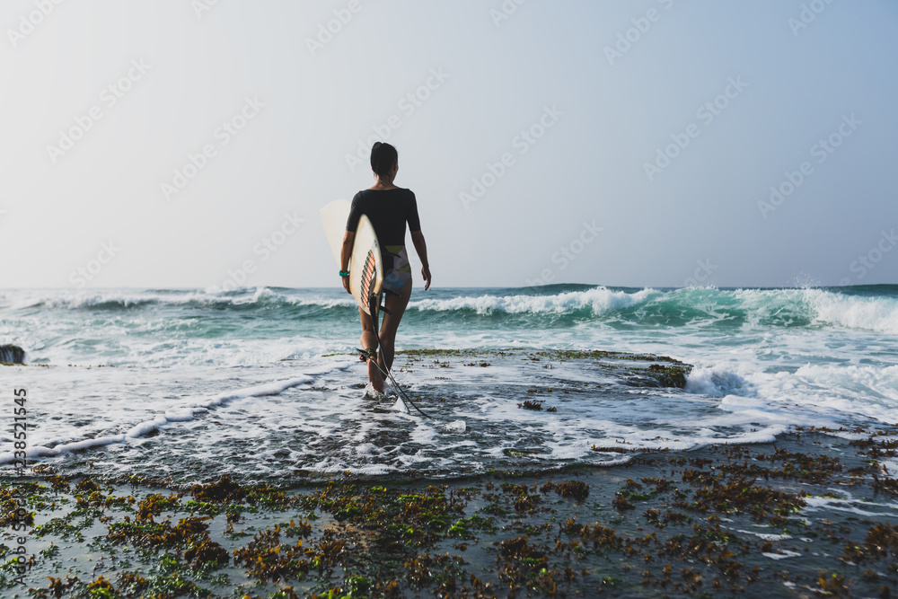 Woman surfer with surfboard going to surf