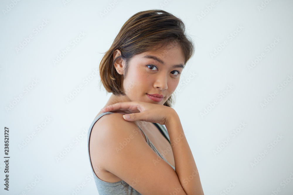 Portrait of confident young woman touching shoulder. Asian girl posing isolated. Bodycare concept Portrait of confident young woman touching shoulder. Asian girl posing isolated. Bodycare concept
