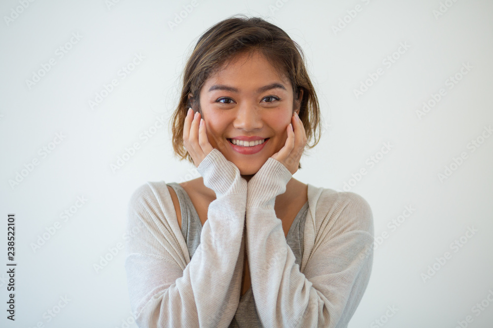 Portrait of happy young woman touching face. Pretty Asian girl looking at camera and smiling. Beauty and bodycare concept Portrait of happy young woman touching face. Pretty Asian girl looking at camera and smiling. Beauty and bodycare concept