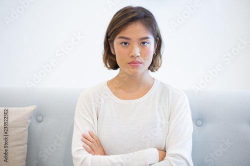 Konstfotografi Portrait of serious woman sitting on coach with folded arms