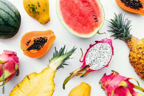 Flat lay tropical fruit layout made of dragon fruit, watermelon, papaya and pineapple on a white background, creative summer food concept