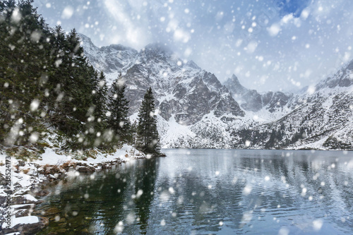 Winter at Eye of the Sea lake in Tatra mountains with falling snow, Poland