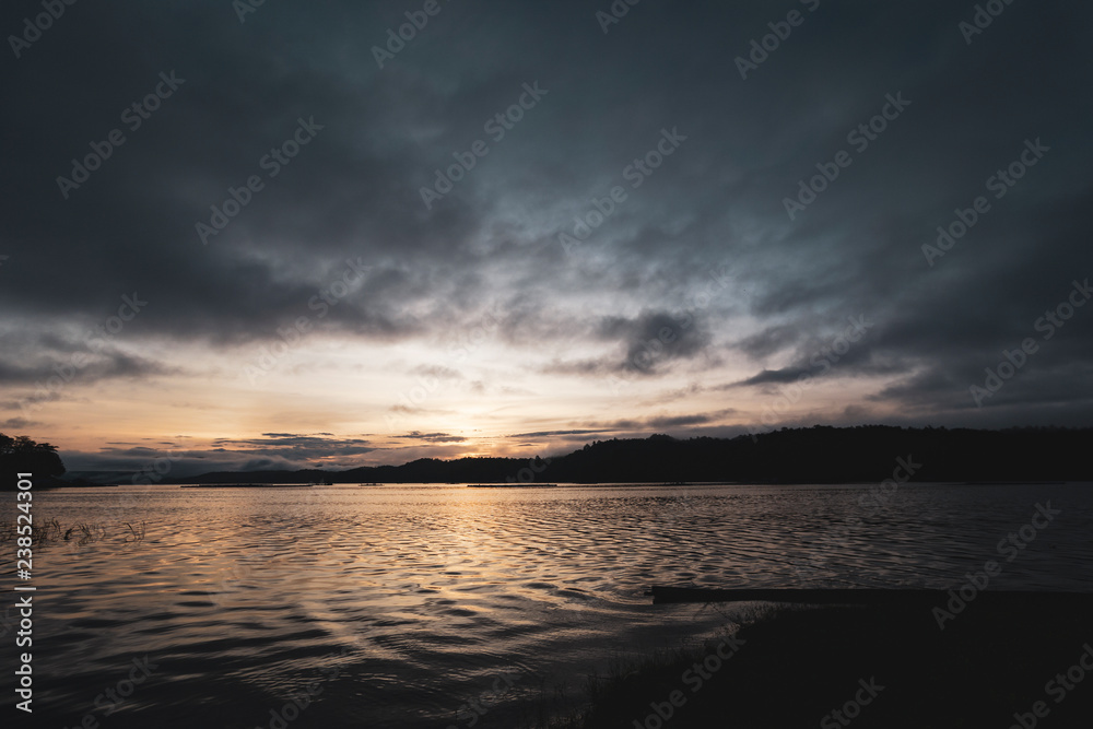 Dawning landscape by a lakeside with beautiful light from the sunrise and dramatic sky