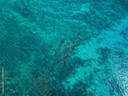 Aerial view of the tropical sea surface with coral reefs on the bottom