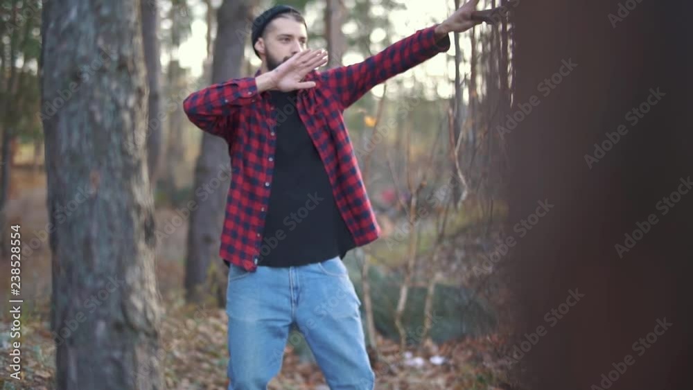 Bearded young man is dancing with axe in the forest. Brutal man with an axe outdoors. Bearded young man is dancing with axe in the forest. Brutal man with an axe outdoors.