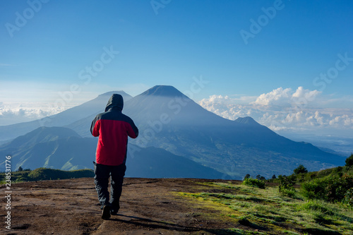 A man in red jacket walks towards the cold misty Sundoro mountain in the morning. photo