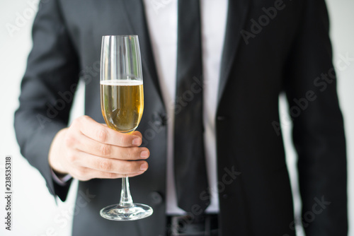 Closeup of business man holding goblet with champagne. Person celebrating event. Holiday concept. Isolated cropped front view on white background.