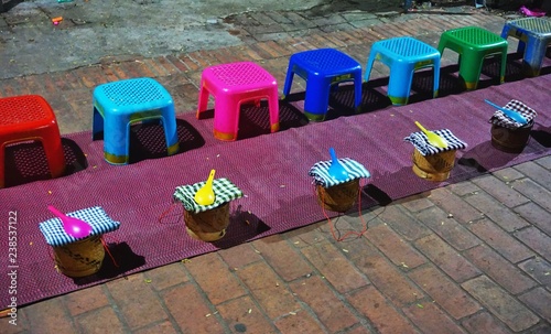 Colorful plastic stools and sticky rice baskets lined up pre-dawn for the morning alms-giving ritual in Luang Prabang, Laos