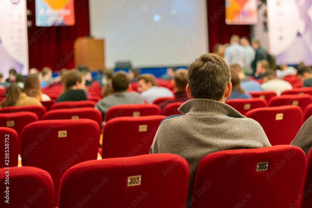 People in the auditorium on a business conferece. person back seating and watching f