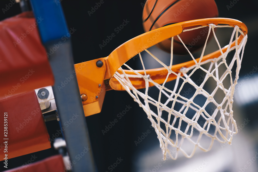 Basketball scoring basket at a sports arena. Scoring the winning points at a basketball game. The orange basketball ball flies through the basket