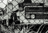 Old wrecked lorries in black and white scene. Abandoned rusty truck in wire fence. Decayed abandoned truck. View from fence to truck. Tragedy and loss. Financial crunch and economic recession concept.