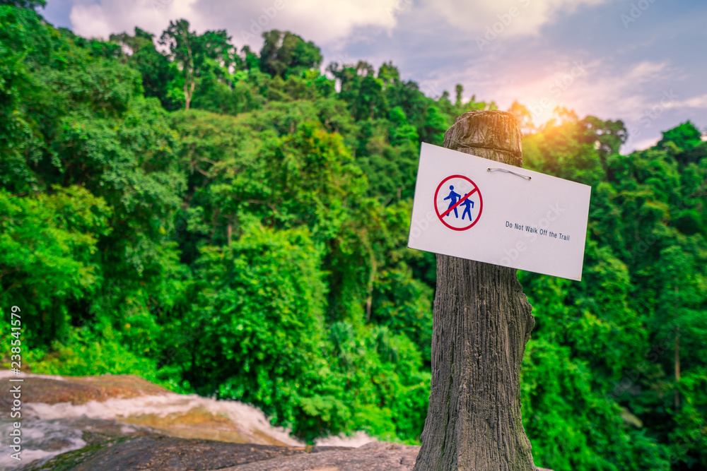 Do not walk of the trail. Warning sign in national park hang on concrete pole at waterfall in green tropical forest. Warning sign for traveler for prevent accident during trail. Sign for safety. Do not walk of the trail. Warning sign in national park hang on concrete pole at waterfall in green tropical forest. Warning sign for traveler for prevent accident during trail. Sign for safety.