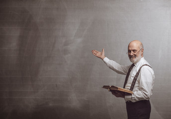 Smiling confident professor teaching and pointing at the blackboard