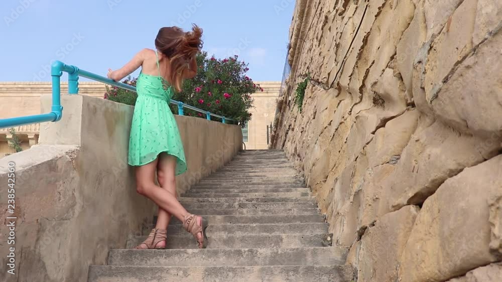 Young girl in summer dress on the stairs / Hair fluttering in the wind/ Valletta, Malta island Young girl in summer dress on the stairs / Hair fluttering in the wind/ Valletta, Malta island