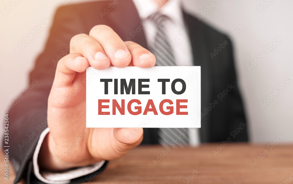 Businessman holding a card with text Time To Engage Businessman holding a card with text Time To Engage