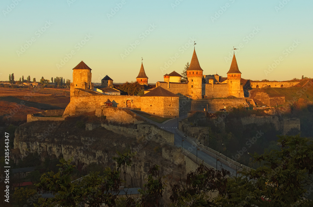 Autumn landscape of medieval Kamianets-Podilskyi castle during sunrise. Famous touristic place and travel destination in Ukraine. Kamianets-Podilskyi, Khmelnitsky region, Ukraine