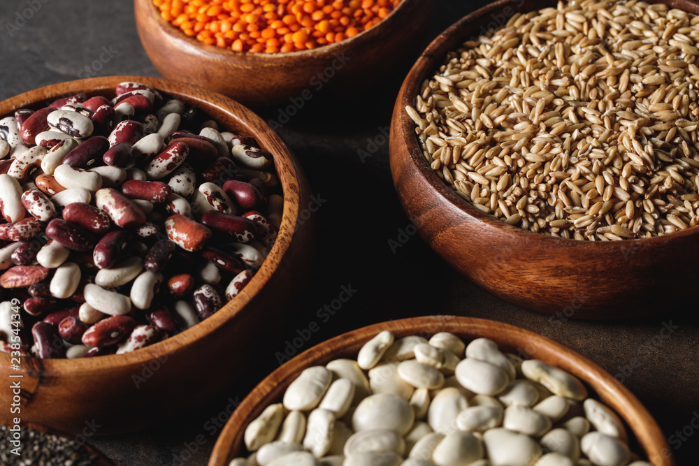 variety of beans in wooden bowls with oat groats on table variety of beans in wooden bowls with oat groats on table