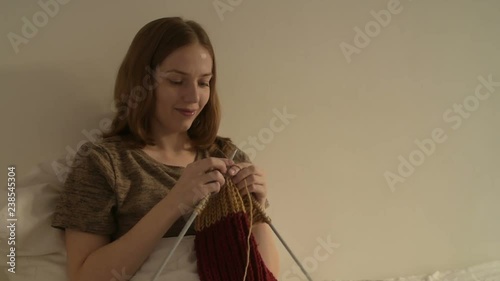 Young woman knitting in bed