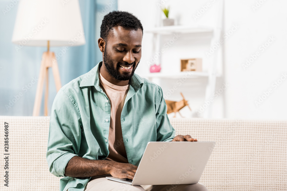 african american man working on laptop in living room