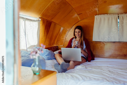 Woman with mug using laptop on bed