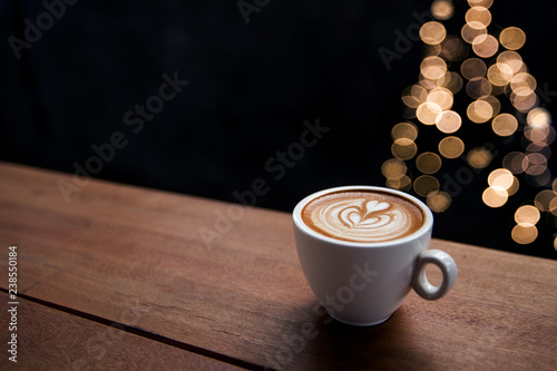 Fototapeta Smaczne cappuccino z rozmytymi światełkami z choinki.