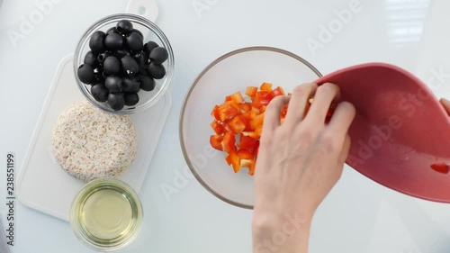 Top view. woman cooking vegetarian low calorie Greek salad, puts vegetables in a bowl. 4K