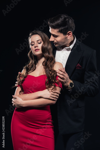 man embracing woman in red dress isolated on black