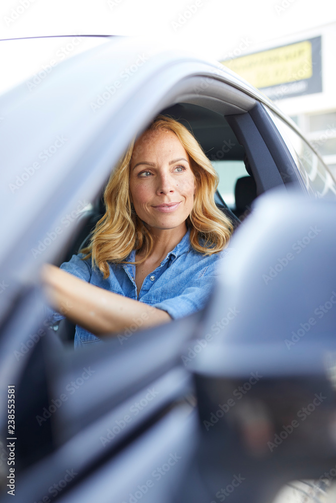 Smiling woman driving car looking out of window Smiling woman driving car looking out of window