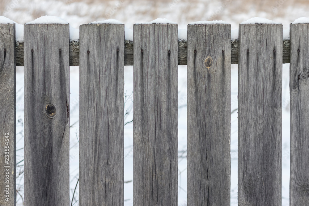 Old unpainted wooden fence with nails in the snow