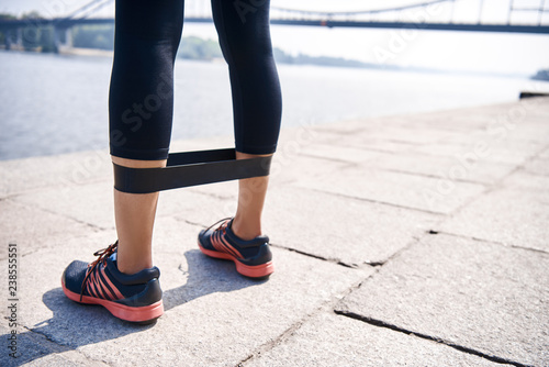 Fotografie Young sporty woman doing exercises with rubber band outdoor.