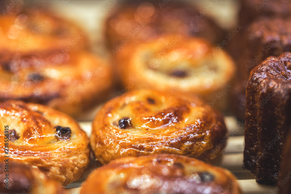 Mouthwatering Danish spiral cinnamon raisin rolls, golden and shiny on display, bakery and cafe concept, sweet indulgence