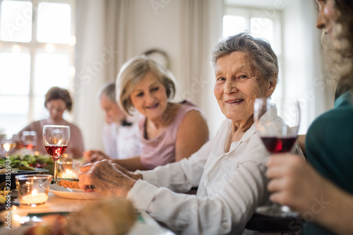 An elderly women with a family sitting at a table on a indoor family birthday party.