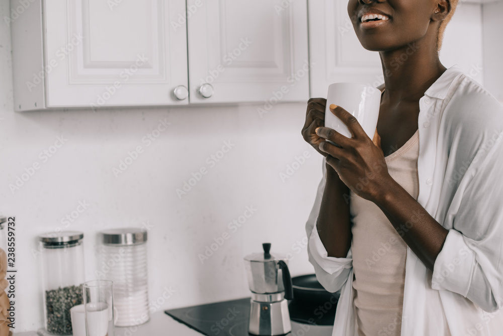 cropped view of cheerful african american woman with cup of coffee cropped view of cheerful african american woman with cup of coffee