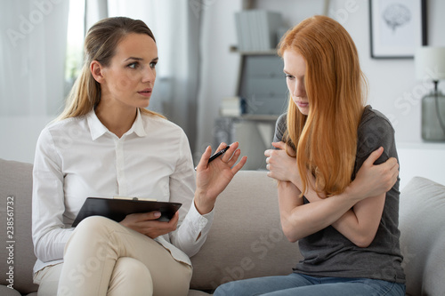 Professional therapist with young teenage red head girl during psychotherapy photo