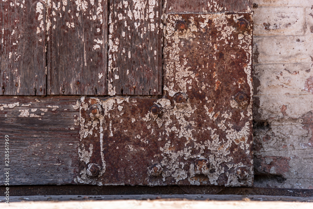 Iron rusted and unpainted angle of a wooden door with a bircks background Iron rusted and unpainted angle of a wooden door with a bircks background