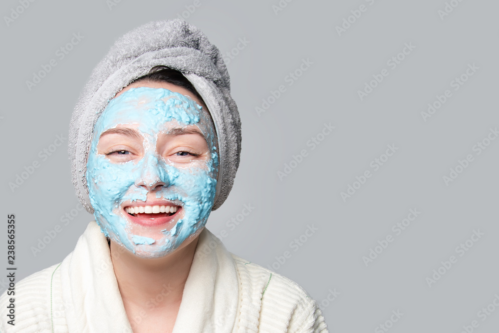 Woman applying facial clay mask at spa salon or at home, skincare theme. Face mask, spa beauty treatment with copy space on gray background. Woman applying facial clay mask at spa salon or at home, skincare theme. Face mask, spa beauty treatment with copy space on gray background.