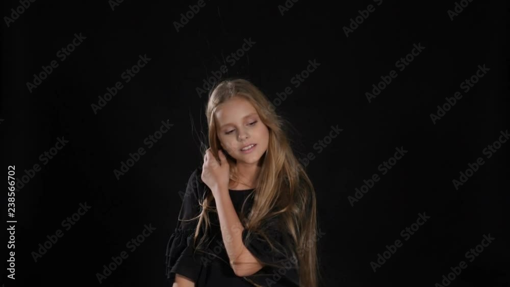 Pretty little model posing in studio isolated on black. White - haired girl looks at camera, smiling, hd
