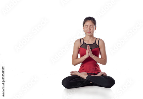 Portrait of young beautiful girl in red sportswear doing yoga practice, sitting cross-legged in sukhasana with hands in Namaste pose, in isolated on white background