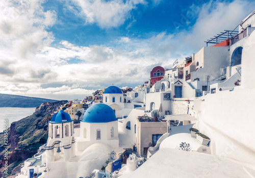 Churches in Oia, Santorini island in Greece, on a sunny day with dramatic sky. Scenic travel background.