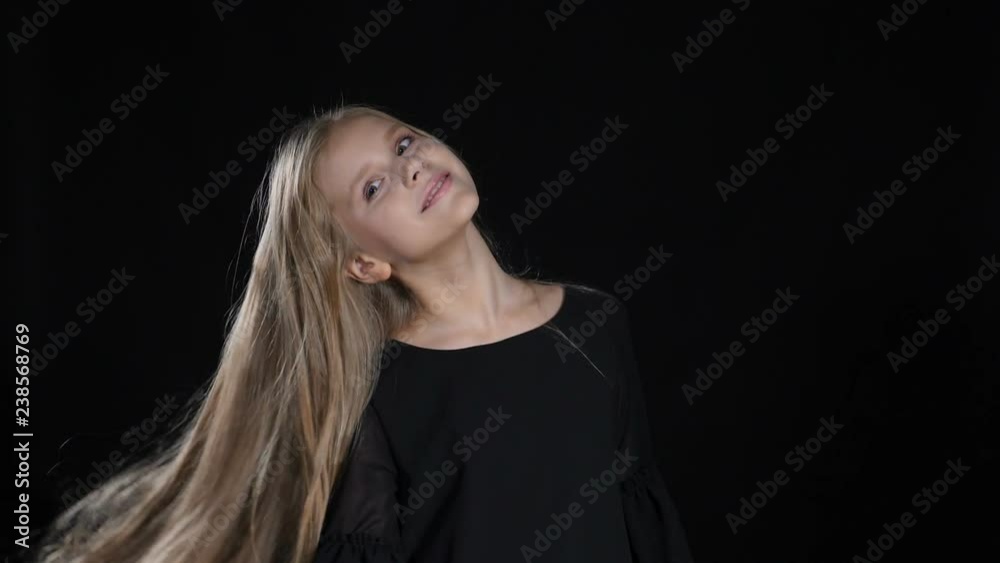 Portrait of little model in studio isolated on black background. Touching her hair in slow motion, looking at camera, posing. hd Portrait of little model in studio isolated on black background. Touching her hair in slow motion, looking at camera, posing. hd