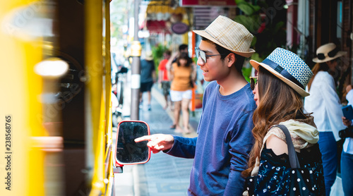 Wallpaper Mural A couple of blogger tourists from Southeast Asia. Visit Phuket in Thailand are Asking Route price from driver in the old town of Phuket during write travel reviews with sunlight in travel concept . Torontodigital.ca