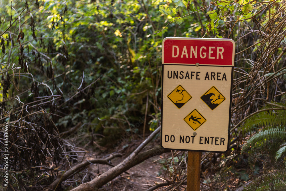 Warning sign on one of the trails due to the danger of landslides, tides or falling in in Southern Oregon, USA