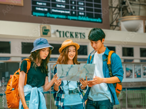 travel concept.group of traveller friend with trikets counter and time table background.asia tourist looking map in terminal at Hualumpong Bangkok train station.
