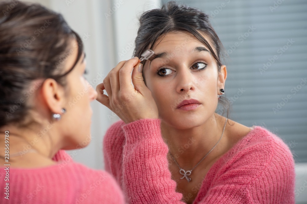 young brunette woman putting makeup in the mirror young brunette woman putting makeup in the mirror