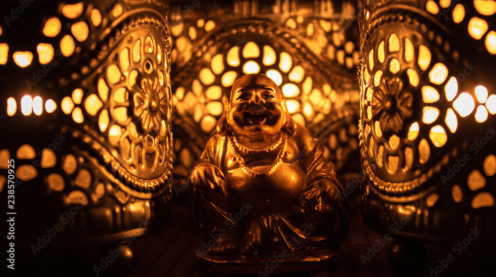 Obraz premium Złota figura mnicha z ciepłym światłem świec.