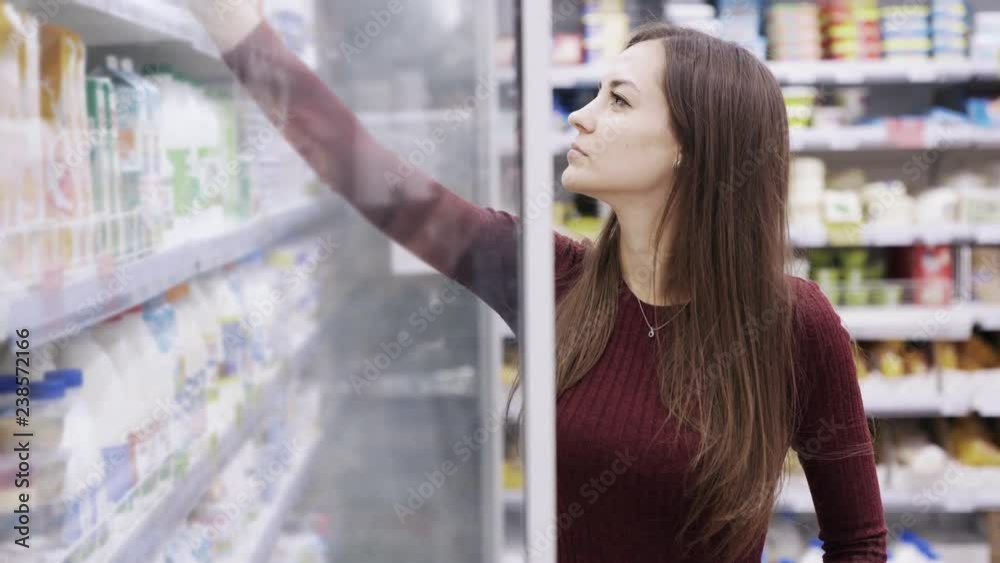 Woman in dress selecting dairy products in fridge at grocery department of shopping mall. Woman in dress selecting dairy products in fridge at grocery department of shopping mall.